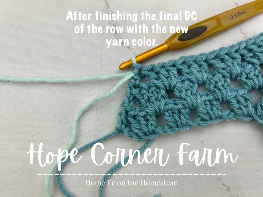 After finishing the final double crochet of the row with the new yarn color