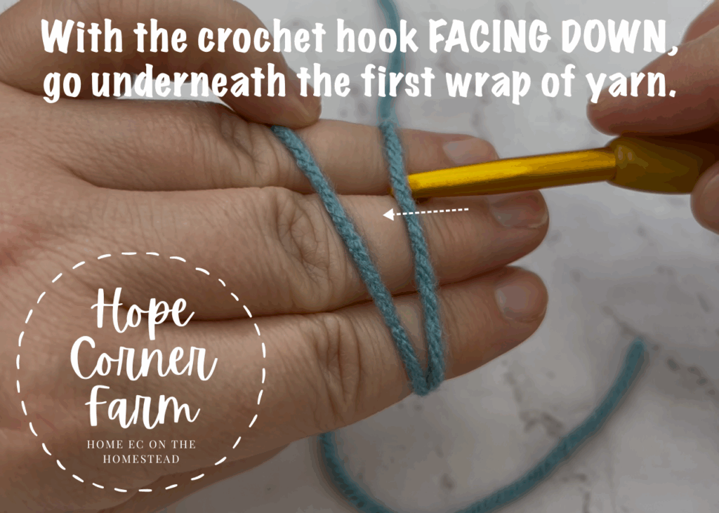 With the crochet hook facing down go underneath the first wrap of yarn
